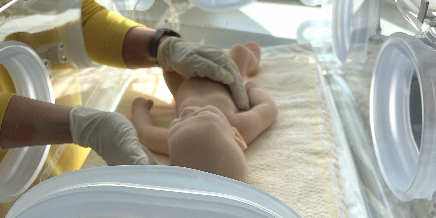 Blick in einen Inkubator, in dem eine Babypuppe liegt.
