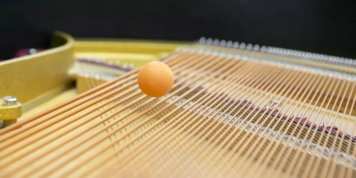 Das Bild zeigt einen kleinen Ball, der über Klaviersaiten hüpft.