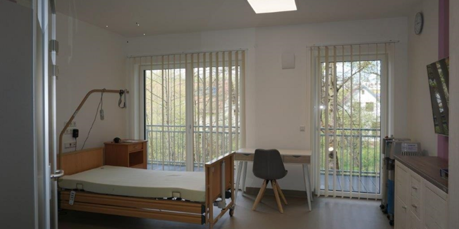 Blick in ein BewohnerInnenzimmer - Krankenbett und Wohnungseinrichtung