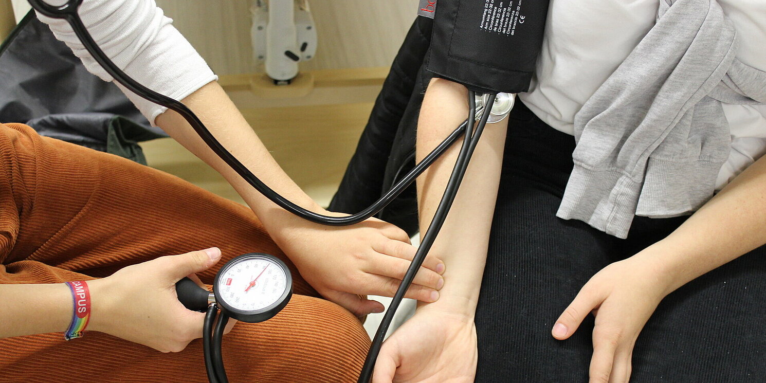 Studierende messen einander gegenseitig den Blutdruck.