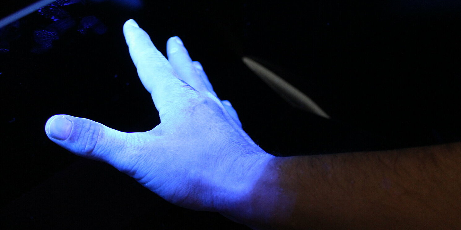 Ein Gerät zeigt mit UV-Licht, an welchen Stellen die Hände erfolgreich desinfiziert wurden.