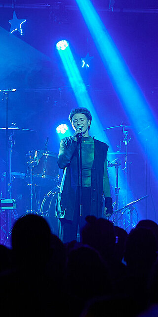 Eine Sängerin steht auf einer Bühne im Rampenlicht.